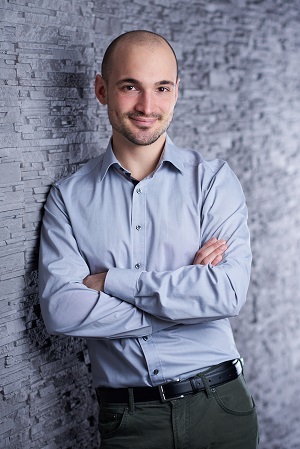 Auf dem Bild ist Michael Simon in einem Hemd zu sehen, wie er sich gegen eine Wand lehnt.